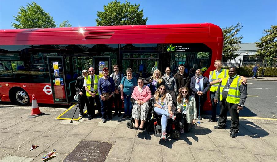 Image of a group of people standing in front of a red bus