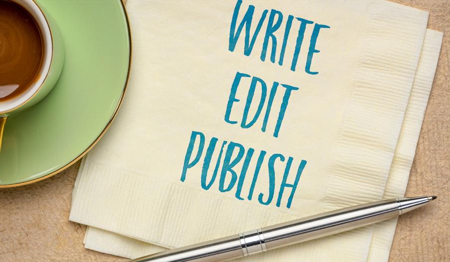 A stock image of a napkin with the words 'Write, Edit, Publish' edited onto it. The napkin is in between a coffee cup and a ballpoint pen.