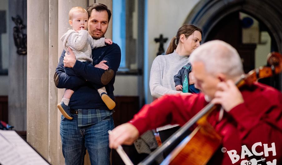 baby and parent watching cellist at a bach to baby concert