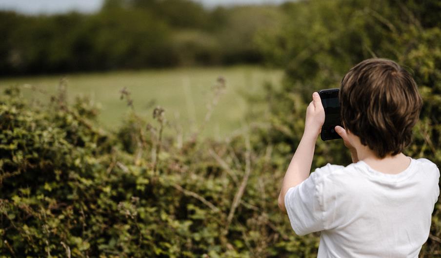 A child taking a photo outdoors. Photo by Annie Spratt