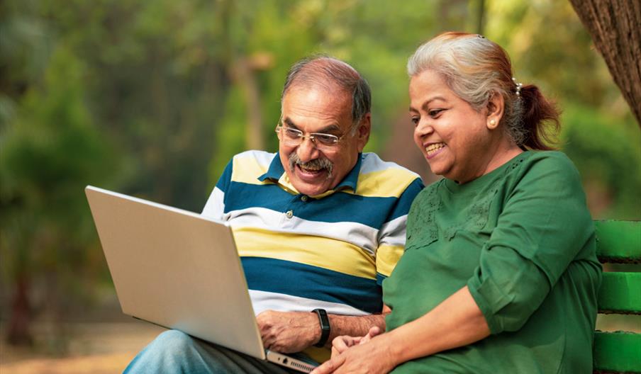 Two people smiling and looking at a laptop together.