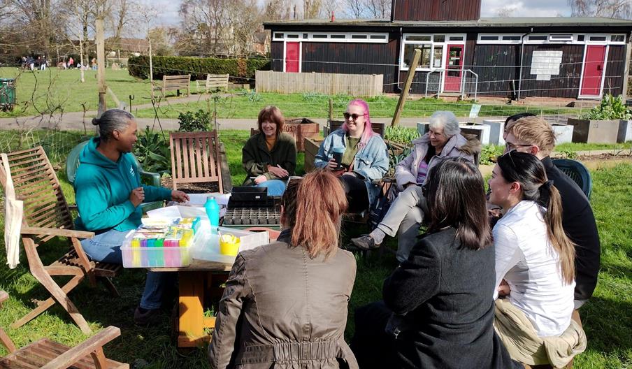 A group of people sitting around a garden table and talking