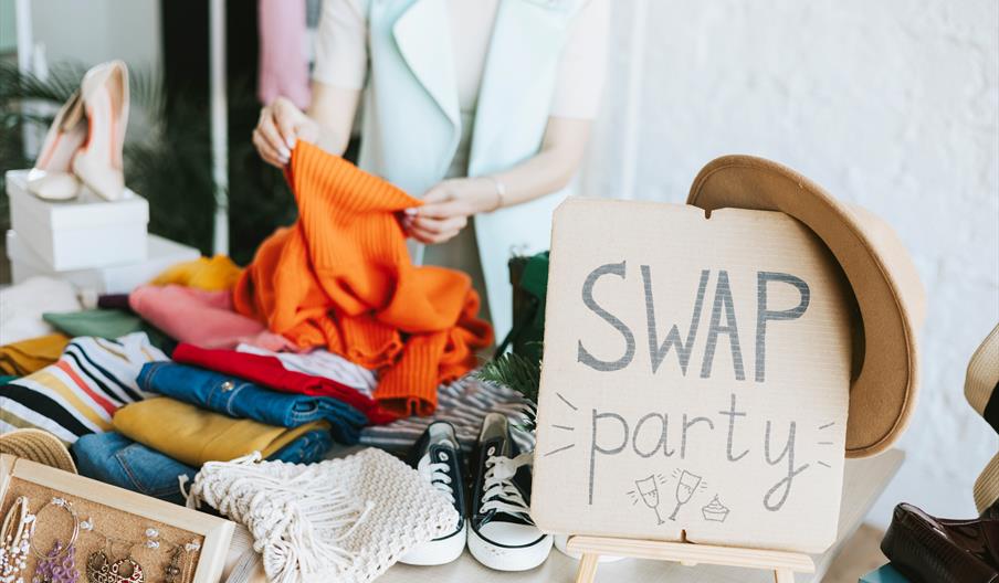 clothes laid on table with clothes swap sign