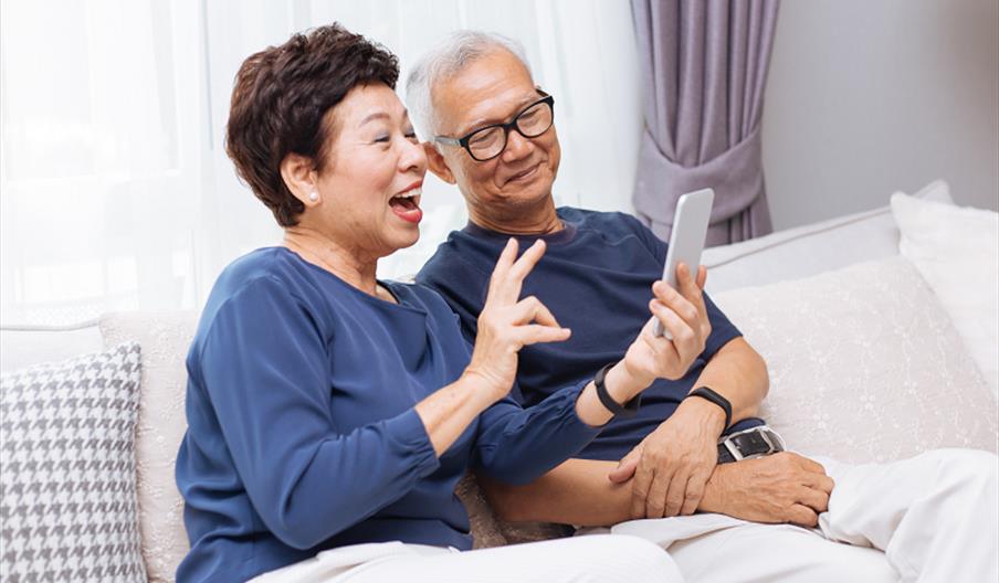 Two people using a smartphone together and smiling.