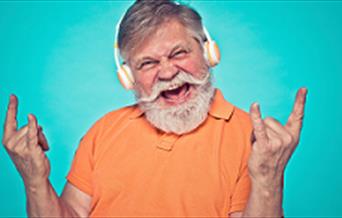 Older man with headphones rocking out to music.