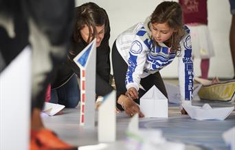 A photograph of two people kneeling down doing a craft activity.