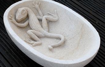 A stone bowl with a reptile carved within the structure