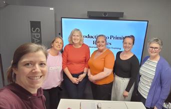 A group of therapists including two osteopaths, a cranial sacral therapist, a massage therapist and a homeopath standing in front of a screen that say