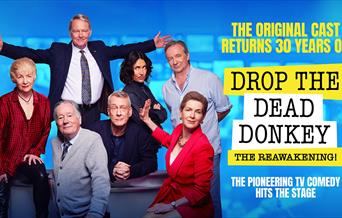 Poster for Drop the Dead Donkey. The original cast poses together on a news desk, to the left of the following text: The original cast returns 30 year