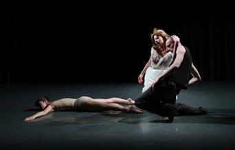 A group of people performing a dance on a dimly lit stage, showcasing various styles and movements.