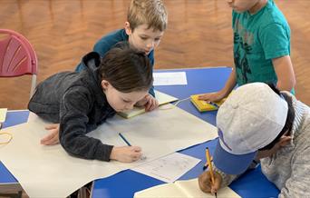 Group of children working on designs round a table.
