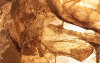 An image of brown waxed paper. It is crumpled and has areas of light and darkness.