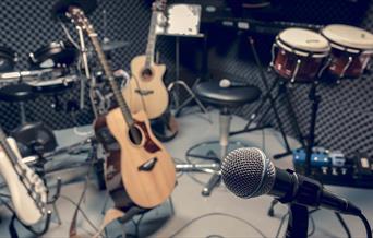 A gray-scale image of a recording studio filled with musical instruments