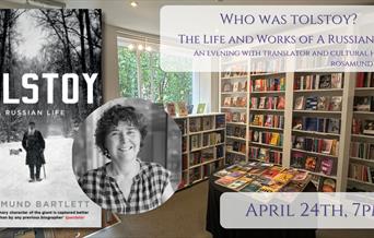Picture of Rosamund Bartlett in front of Tolstoy: A Life bookcover in front of backdrop of the bookshop