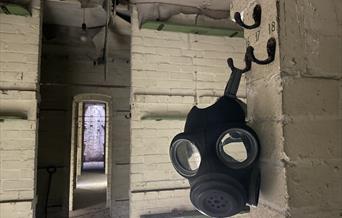 Image of men's sleeping quarters with gas mask in foreground