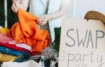 Clothes with a sign saying 'Swap Party'