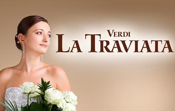 Poster for Ellen Kent's production of Verdi's La Traviata. A young brunette woman dressed in white looks to the right, holding white roses.