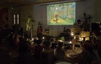 A photograph of young children watching 'Where the Wild Things Are' on a projector screen.