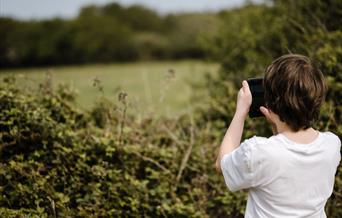 A child taking a photo outdoors. Photo by Annie Spratt