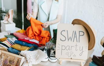 clothes laid out on table with clothes swap sign