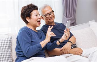 Two people using a smartphone together and smiling.