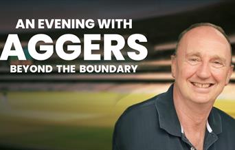Poster for An Evening with Aggers: Beyond the Boundary. Jonathan Agnew is smilling at the camera against the background of a cricket pitch; he is wear