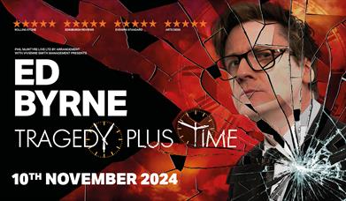 Poster for Ed Byrne: Tragedy Plus Time. Ed Byrne is smartly dressed in a suit with a red background behind him. There is the effect of smashed glass o