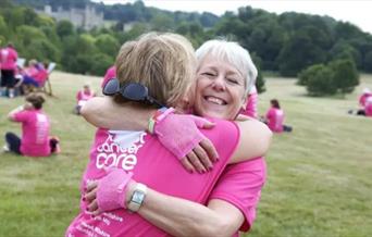 Pink Ribbon Walk - Two ladies in pink hugging in a park