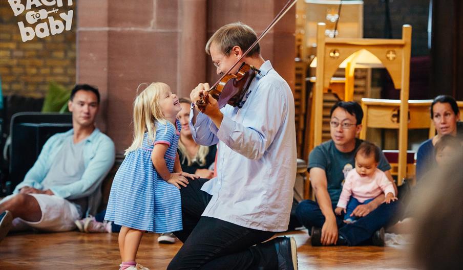 child greets violinist at bach to baby concert child greets violinist at bach to baby concert