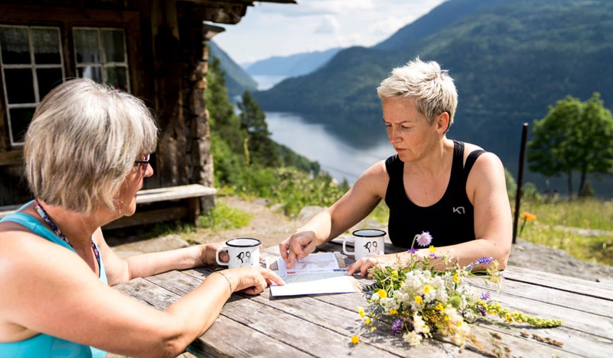 2 damer som sitter ved et bord ved Rui-plassen og ser på kart