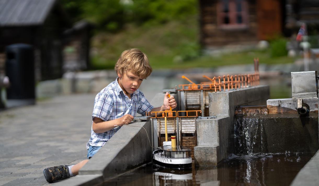 Gutt slusar båt i kanalparken i Eidsborg.