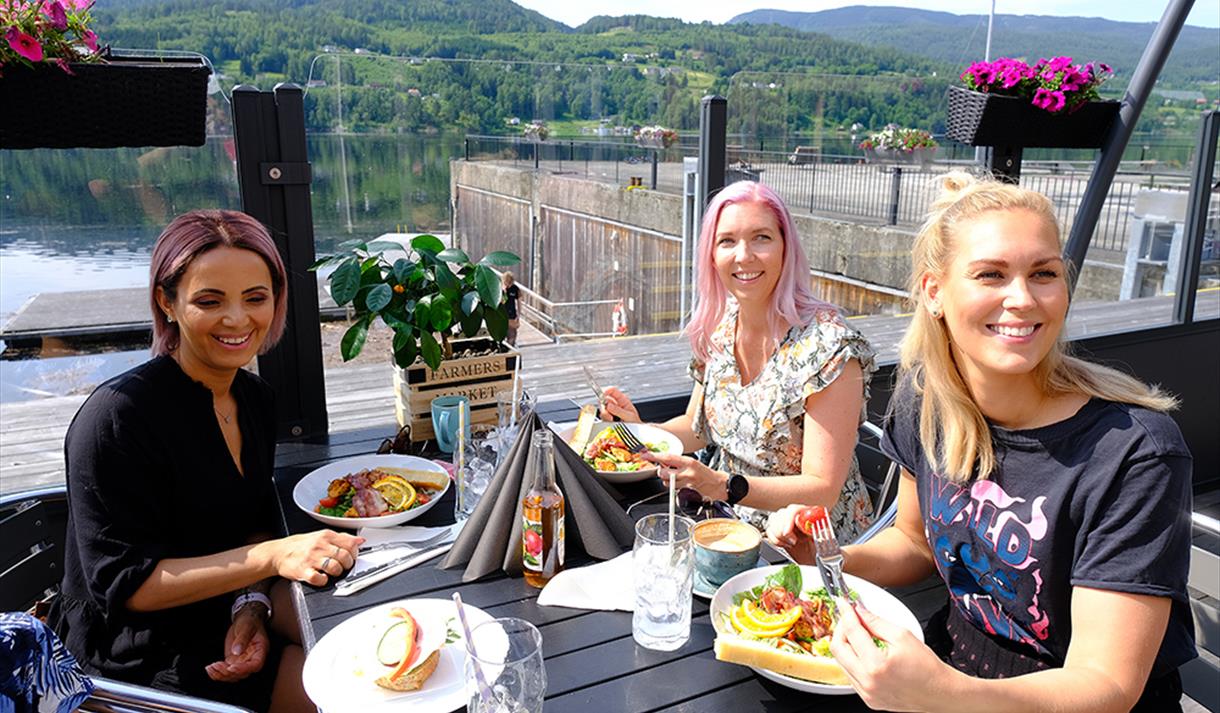 Tre kvinner spiser mat og koser seg på uteserveringen til Dany's Café i Bok & Blueshuset i Notodden. Foto