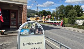 Skilt utenfor Ulefoss Turistkontor, med M/S Henrik Ibsen i bakgrunn i Ulefoss sluser