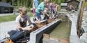 Barn sluser båter på miniatyrutgaven av telemarkskanalen på kanalparken på Vest-Telemark Museum i Eidsborg