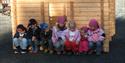 Gruppe med barn foran et laftet hus på Vest-Telemark Museum Eidsborg