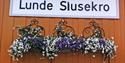 skilt til Lunde Slusekro med blomster under