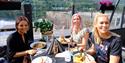 Tre kvinner spiser mat og koser seg på uteserveringen til Dany's Café i Bok & Blueshuset i Notodden. Foto