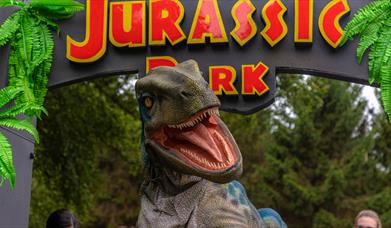 A velociraptor pictured in front of the Jurassic park gate.