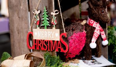 A wooden Merry Christmas sign is shown on a craft stall