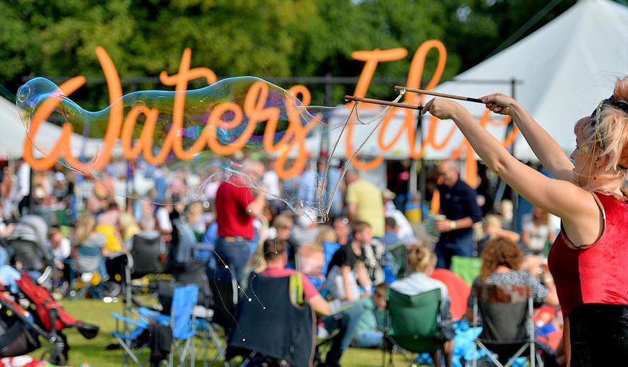 Large bubble blower with Waters Edge Festival sign in the background