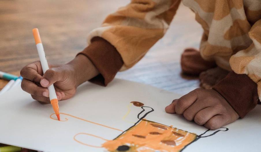 Picture of child drawing an orange character