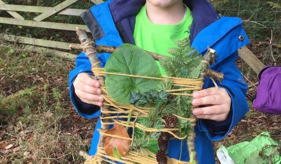 Little boy showing he nature collage made of natural objects