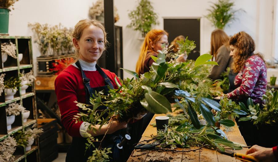 A woman smiling with a hand made Christmas wreath