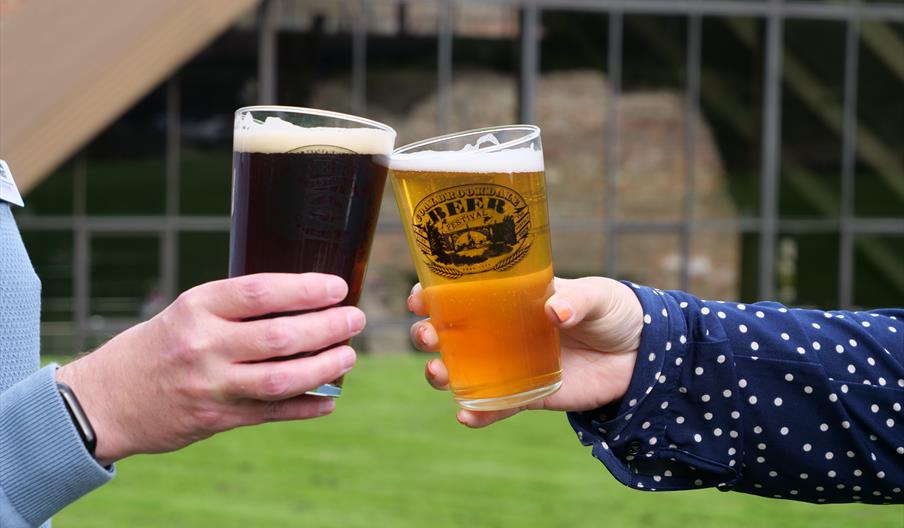 Two hands holding two glasses of beer.