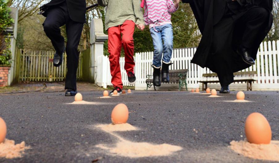 A group of four, shown from the waist down taking part in Victorian egg dancing.