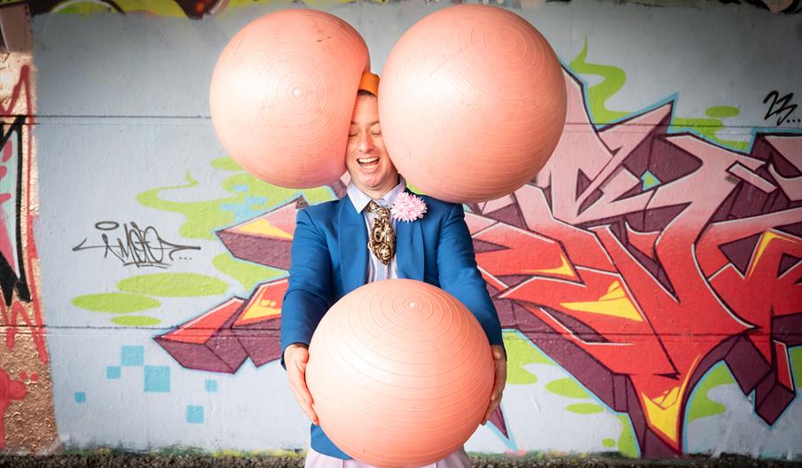 A photo of performer Darryl J Carrington on stage with three large gym balls.