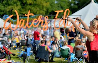 Large bubble blower with Waters Edge Festival sign in the background