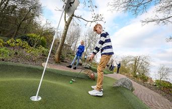 Young people playing adventure golf on a sunny day