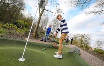 Young people playing adventure golf on a sunny day