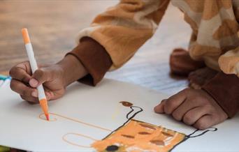 Picture of child drawing an orange character